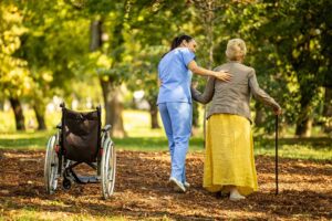 An elderly resident sits in a cozy assisted living room with two family members offering comfort and companionship.