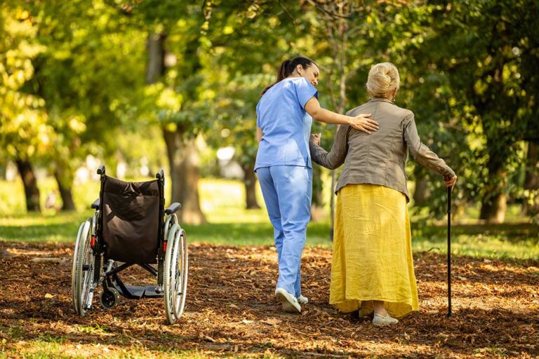 An elderly resident sits in a cozy assisted living room with two family members offering comfort and companionship.